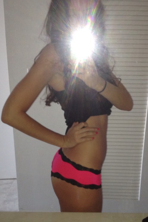 Brunette with flat abs, perky booty, and slim sexy hot body takes selfie in black top and pink panties