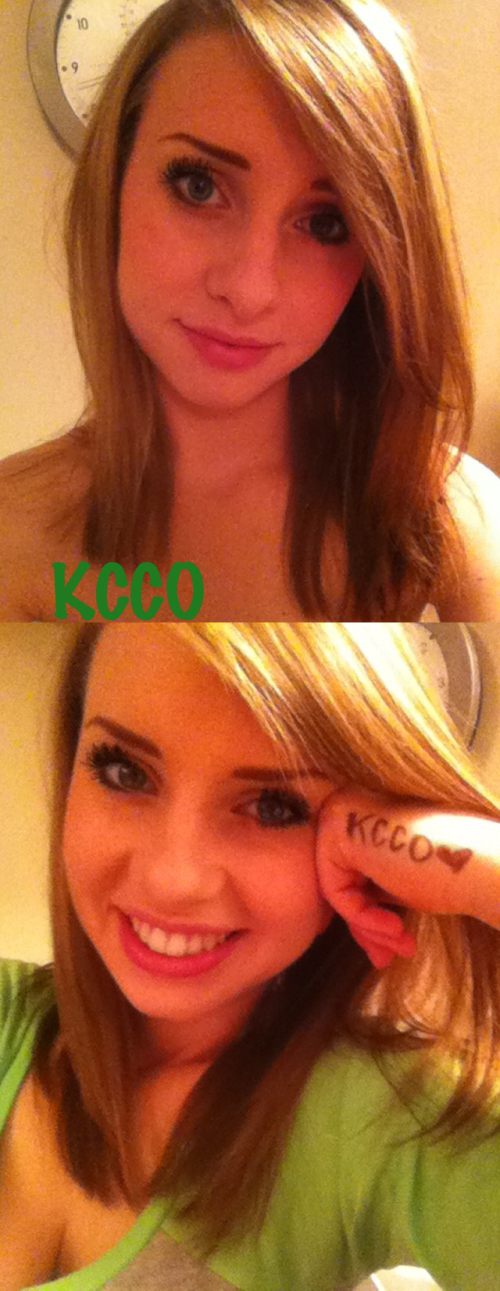 Pretty light-eyed brunette with KCCO written on hand takes selfie in cleavage showing green top