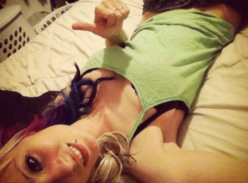 Blonde with colored red/blue hair and slim sexy body takes selfie on bed in green top