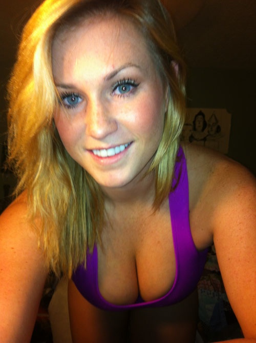 pretty girl with sterling gray eyes exposes her sexy cleavage in purple top with a lovely smile.