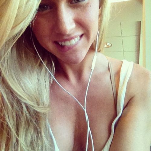 pretty woman with golden hair poses with a lovely smile with headphones in the ears.
