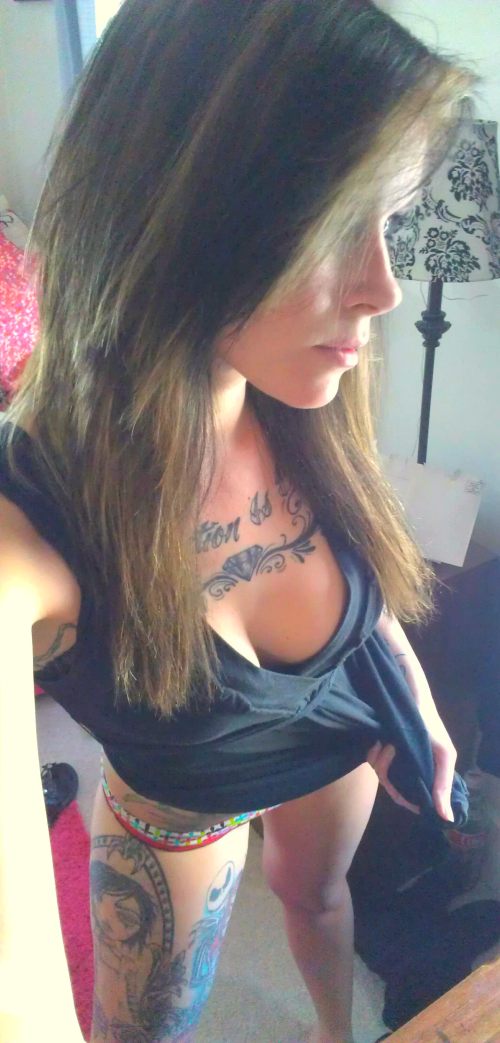 young girl in black top with tatoo on her body and skinny legs poses for a selfie