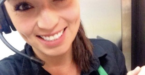 Brunette takes selfie in black top, cap, and microphone headset