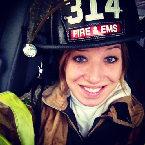 Light-eyed blonde takes selfie in EMS and firefighter helmet and overalls