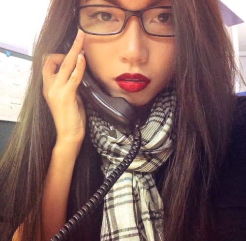 Brunette with red lips takes selfie in glasses, black top, and black/white scarf