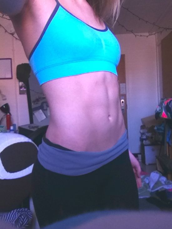 Blonde with perky boobs and flat abs takes selfie in blue sports bra and black yoga pants