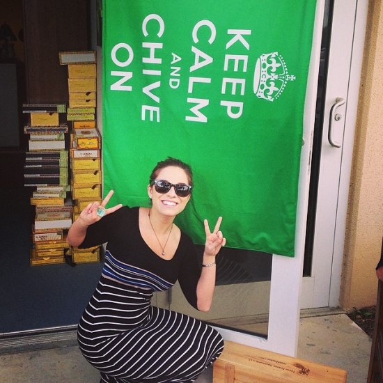 cute girl in sunglasses and black and white striped dress doing peace signs underneath KCCO flag