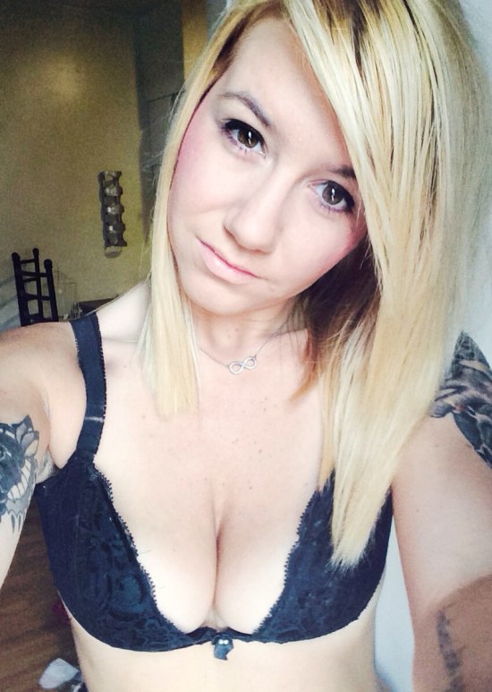 selfie of blonde in black lace bra with tattoos on her arms