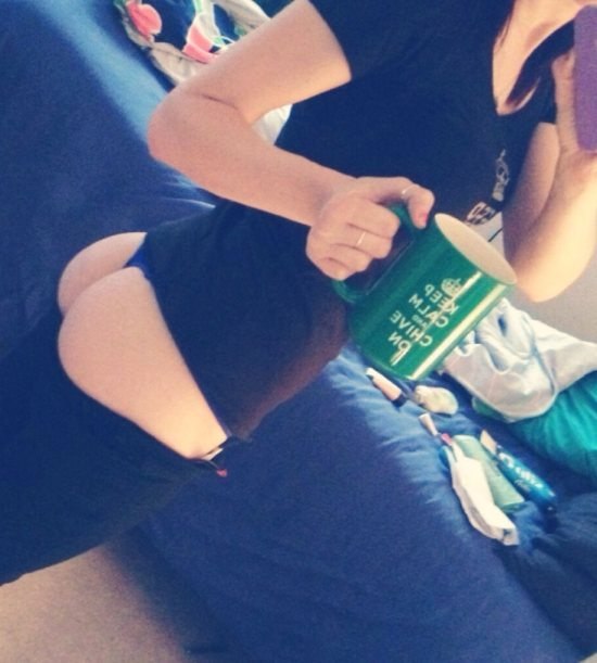girl holding green KCCO coffee mug with pants down showing her butt