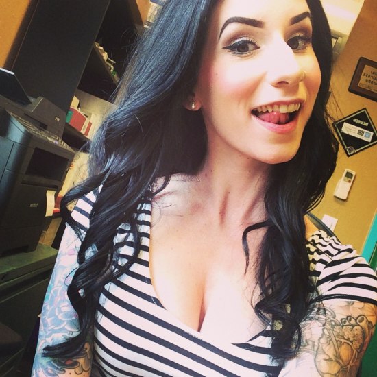 Girl with black hair and tattoos on her arms wearing a black and white striped shirt