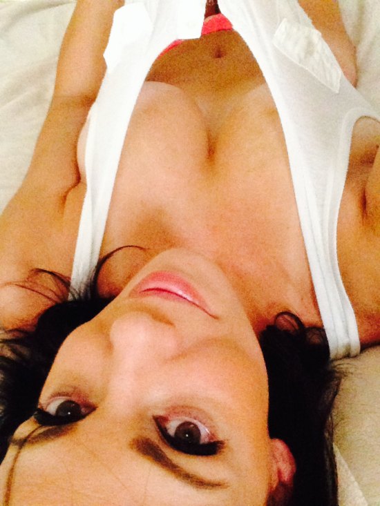 Girl in white tank top laying down and tugging the shirt