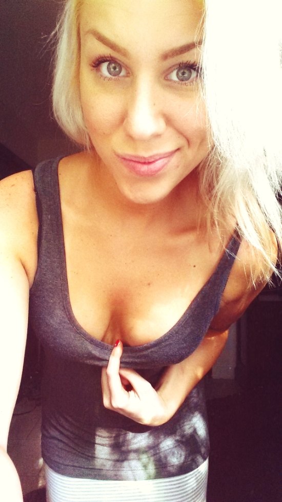 Blonde girl in black tank top pulling down to show cleavage