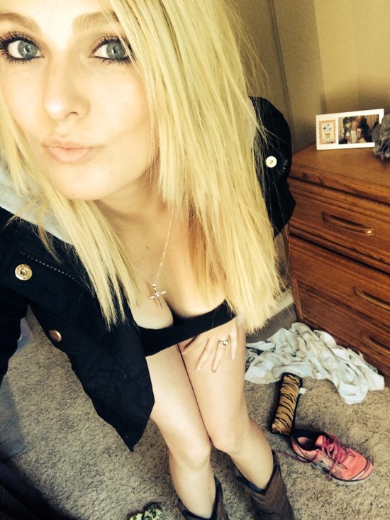 hot blonde girl in black jacket bending down to show cleavage