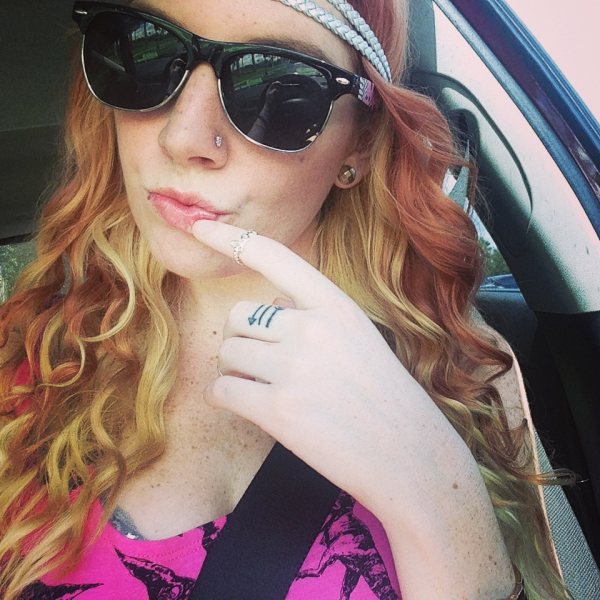 Pretty blonde woman takes her selfie with curly hair,wearing sunglasses and touches her lips