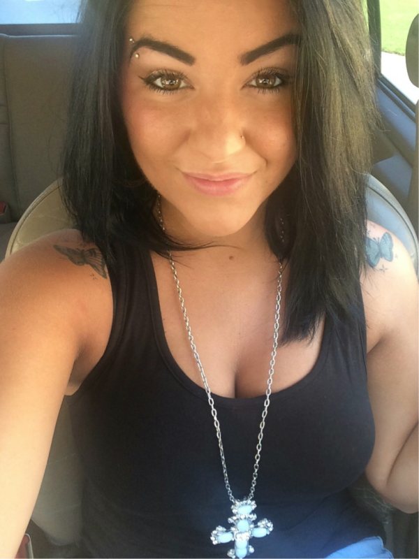 Hot woman with tattoo on her shoulder takes her selfie in a car