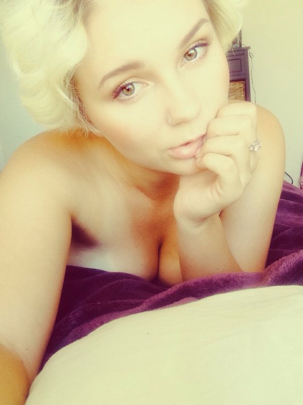 Blonde girl in bed with cleavage