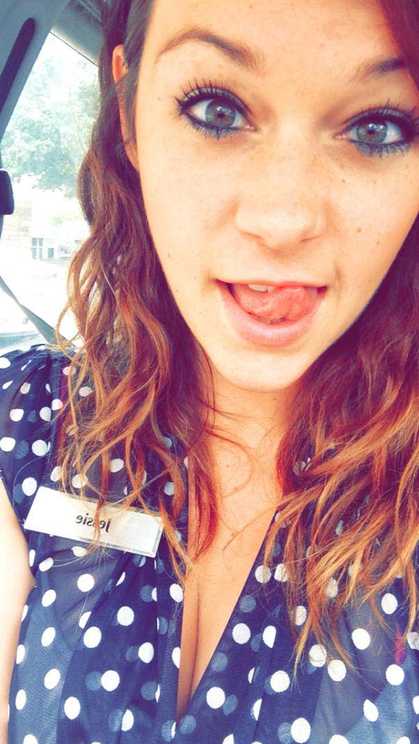 Pretty light-eyed brunette sticks out tongue and takes selfie in cleavage showing blue/white polka dotted top