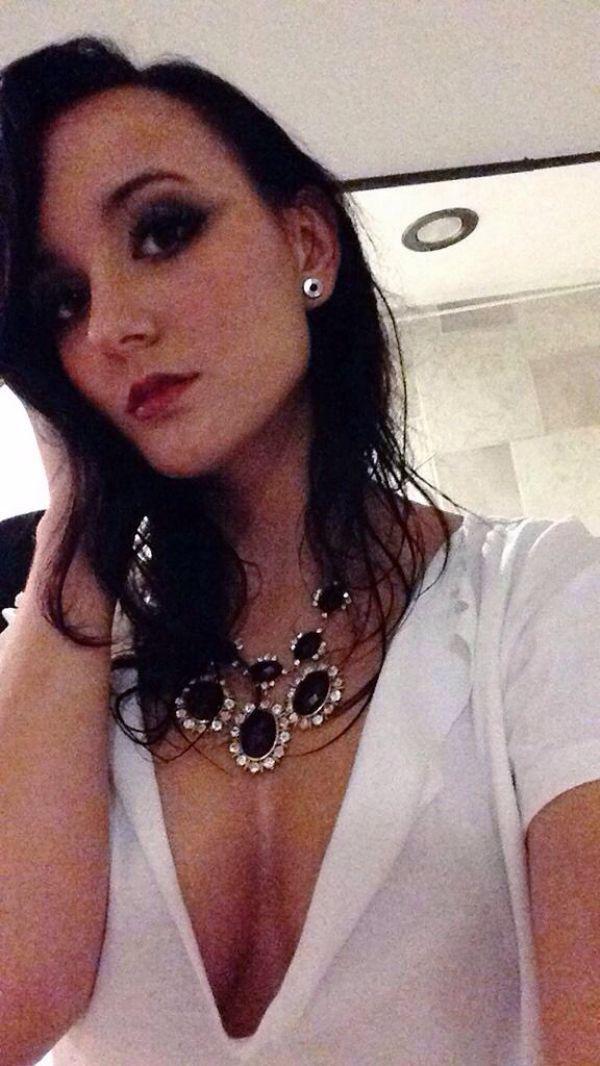 Pretty brunette with red juicy lips and perky boobs takes selfie in jewelry and cleavage showing white top
