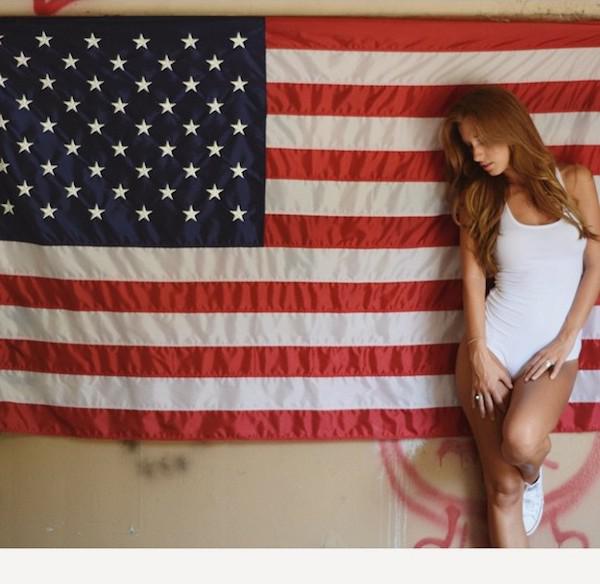 Pretty blonde with slim sexy curvy hot body poses with the American flag in white swimsuit