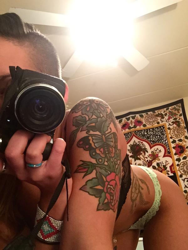 Tattooed brunette with slim sexy body takes selfie with camera in black and green lace lingerie