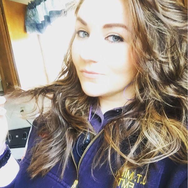 Pretty brunette with flowing tresses and light eyes takes selfie in blue jacket and lavender top