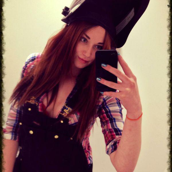 Pretty light-eyed brunette with perky tits and sexy hot body takes selfie in black helmet and dungarees and cleavage showing blue/pink/white checked shirt