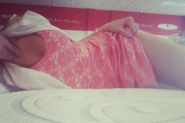 Brunette with slim sexy hot curvy body takes selfie on bed in little pink dress and white jacket