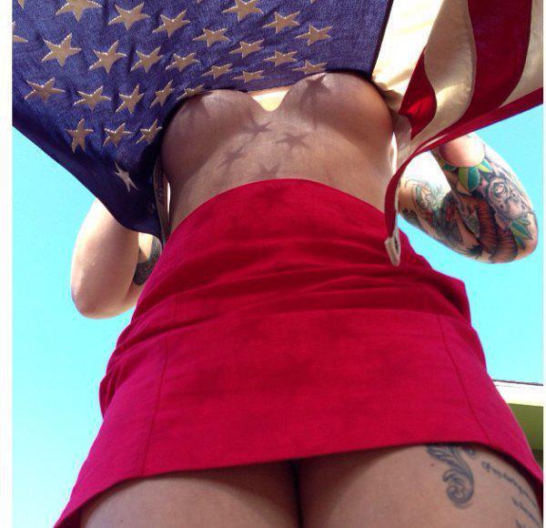 Tattooed girl with sexy hot body poses in underboobs showing stars and stripes top and pink tight mini skirt