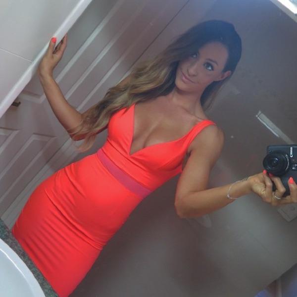 Pretty brunette with slim sexy hot body takes selfie with camera in cleavage showing tight red dress