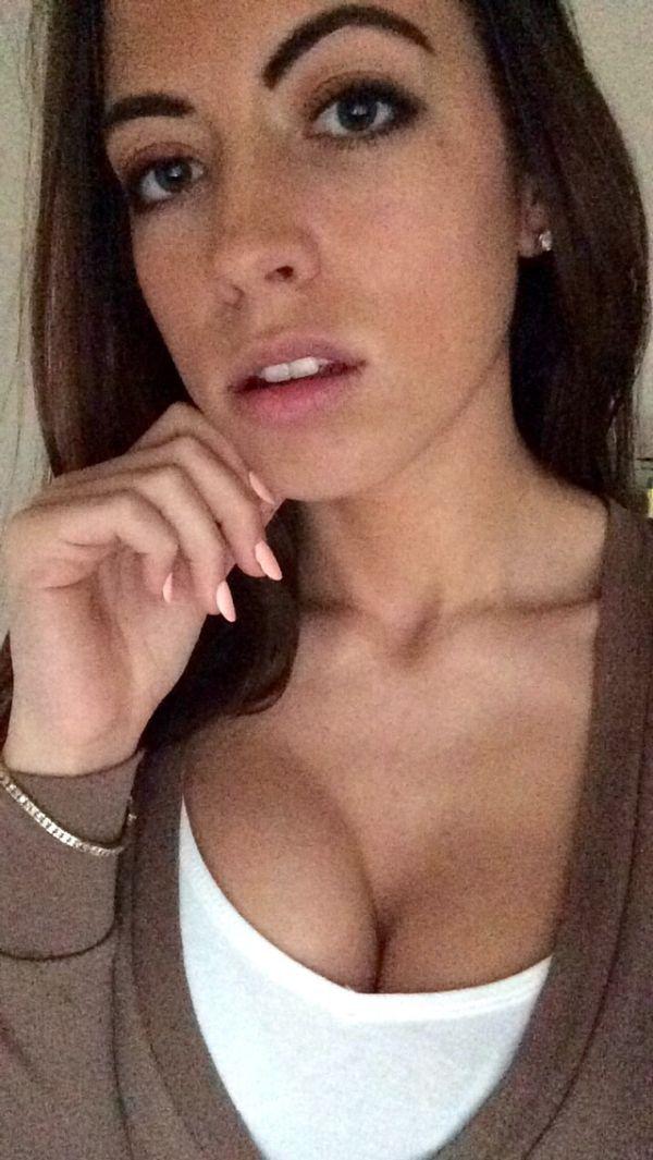 pretty girl with thick eyebrows and sexy black eyes takes busty boobs selfie in white brown top