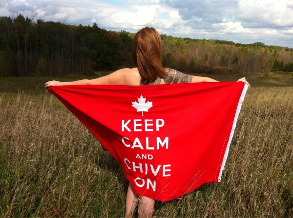 Tattooed girl strikes a pose showing KEEP CALM AND CHIVE ON banner,standing on dry grass field