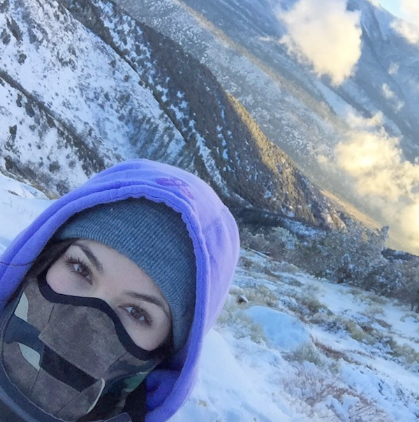 pretty girl takes Snowy selfie with snow covered mountains in background