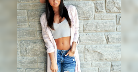 Gorgeous brunette with perky boobs, flat abs, and slim sexy hot body poses in beige hat, cleavage showing white crop top, and blue ripped jeans