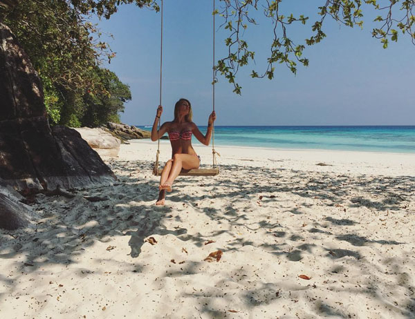 gorgeous girl swings at the beach while wearing two piece, strapless bikini to show her sexy bikini body