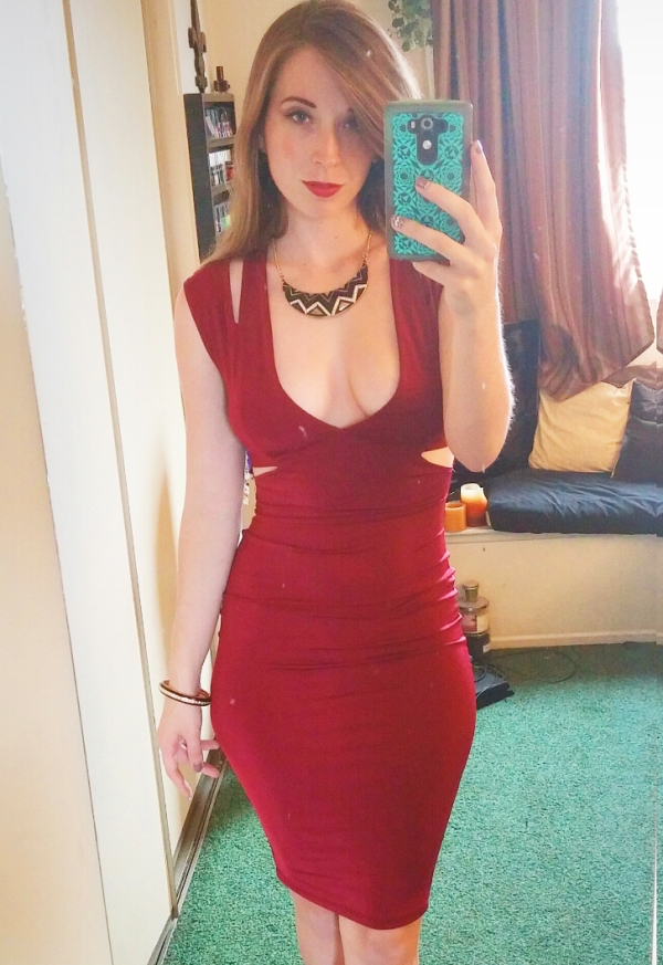 Sexy lady in all-red costume and bright red lipstick, takes a selfie.