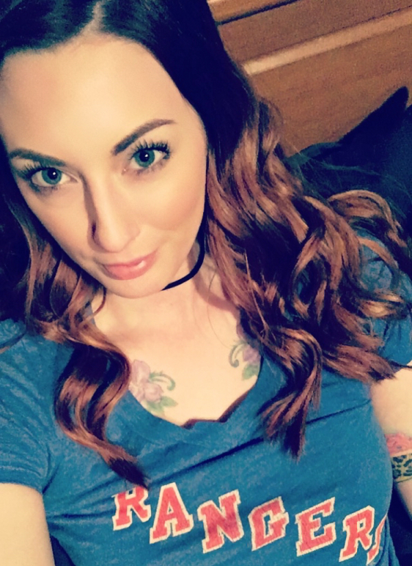 Beautiful young lady clicking a tattoo selfie to show her floral chest tattoo in blue RANGERS top
