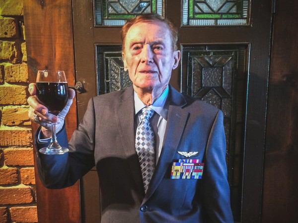 Old sailor in grey tux, holding up a glass of wine