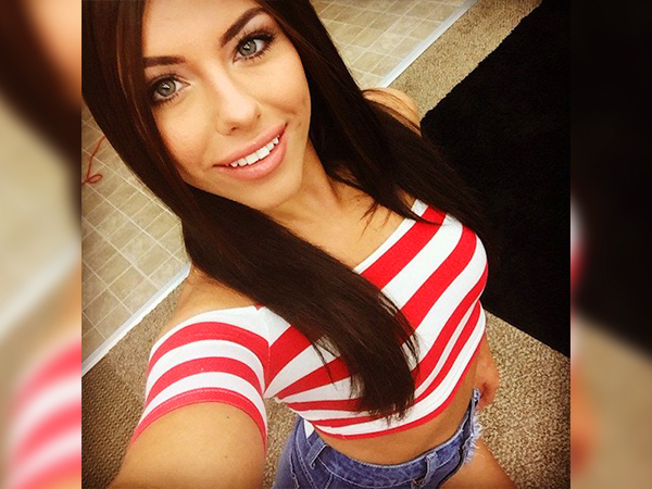 Gorgeous brunette with beautiful light eyes and juicy full lips takes selfie of perky tits and slim sexy body in red/white striped crop top and blue denim shorts