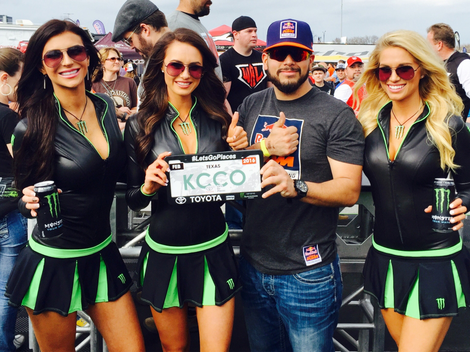 Sexy 'Monster Energy' in deep neck faux leather tight tees and mini skirts pose with a man holding a KCCO sign!