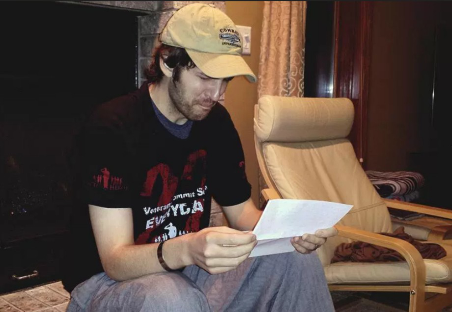 A man in a black tee appears to be moved by a piece of emotive message in a letter