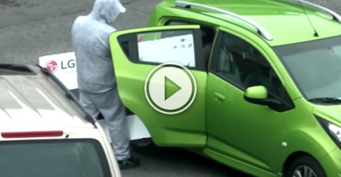 Man trying to cram an LG HDTV into his green Chevrolet car!