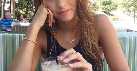 Beautiful girl drinking a cold coffee in an open air caf�� smiles for the photo