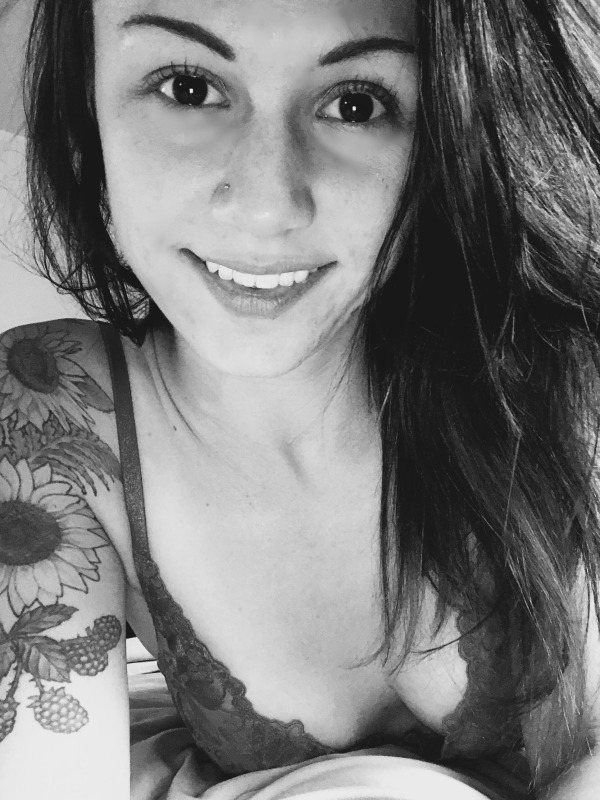 Girl with beautiful eyes and tattoos takes a selfie in cleavage showing lace bra.