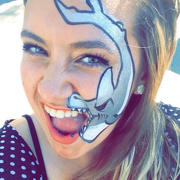 Crazy teen girl having fun with a shark tattoo on her face