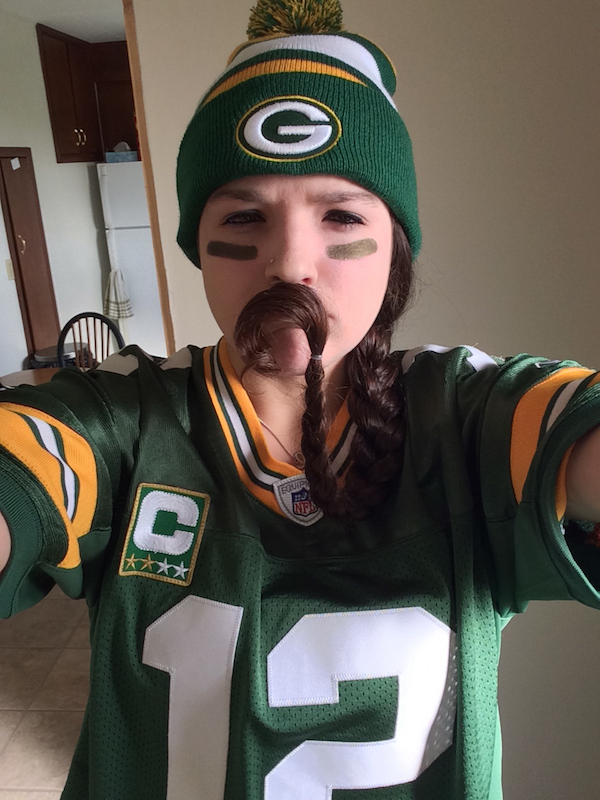 Funny fan of NFL team green bay packers wearing team logo green t-shirt and woollen cap put her hair like mustache over lips