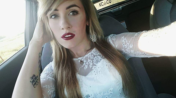 Blonde with dark lips and white dress takes a selfie in the car