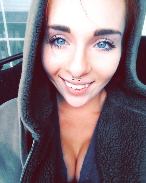 Girl with blue eyes and septum ring shows her bobs in a hoody