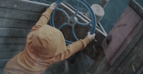Kid in brown hoodie manning the steering wheel in a boat.