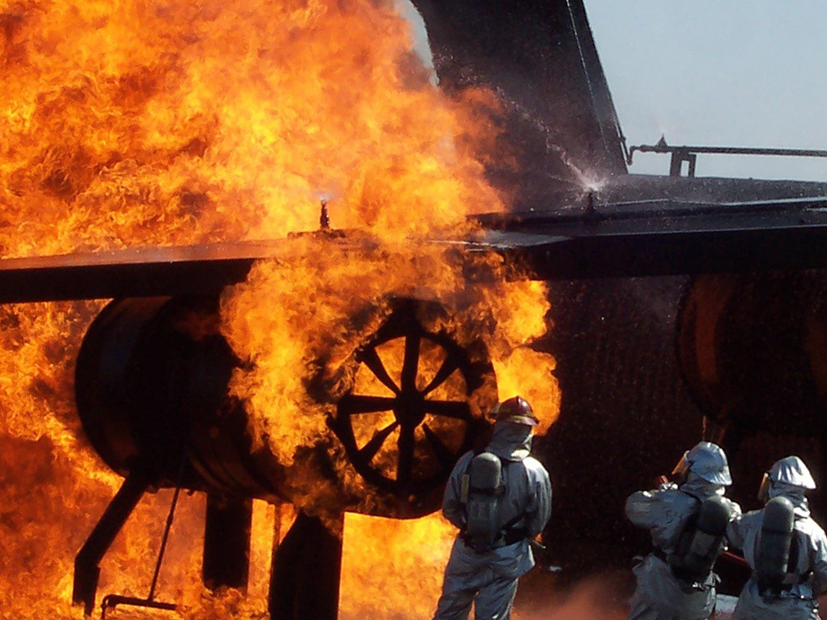 Firefighters in silver protective suits look at a raging fire!