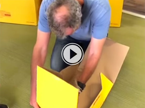 A man in blue tee searches through a yellow box!
